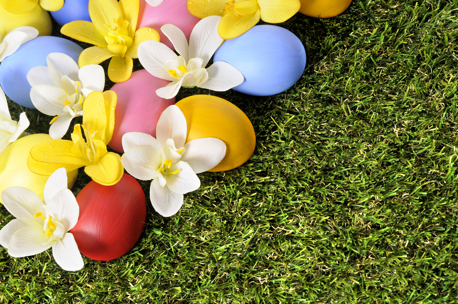 Easter background with hand painted eggs hidden in flowers with copyspace.